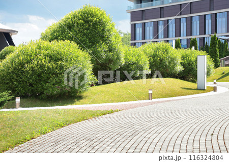 Trimmed green bushes and a building. Landscaping and city holiday in summer. Landscape, background and hotel.  116324804