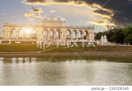 Vienna, Austria, August 20, 2022. The Gloriette sits atop the hill in the gardens of Schonbrunn Palace. People on the tour route at sunset. Vienna, Austria, August 20, 2022. The Gloriette sits atop the hill in the gardens of Schonbrunn Palace. People on the tour route at sunset. 116326140