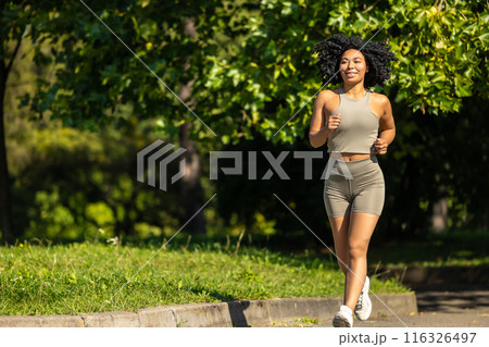 Woman in summer sportswear running in a sunny par and looking focused 116326497