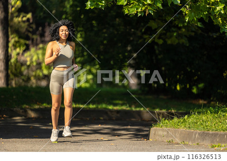 Woman in summer sportswear running in a sunny par and looking focused Woman in summer sportswear running in a sunny par and looking focused 116326513