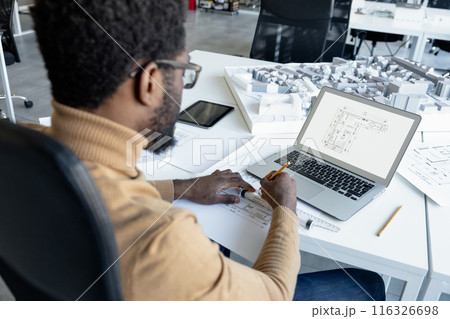 Man architect working with software on laptop using technical drafts drawings at office workplace 116326698
