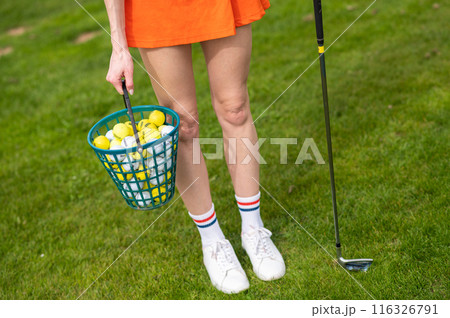 Woman golfer with golf balls on green summer field Woman golfer with golf balls on green summer field 116326791