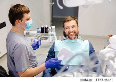 Handsome male patient looking at his beautiful smile sitting at the dental office 116326821