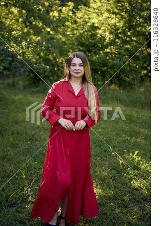 portrait of a beautiful 30-year-old woman with long blond hair in a red dress in a park portrait of a beautiful 30-year-old woman with long blond hair in a red dress in a park 116328640