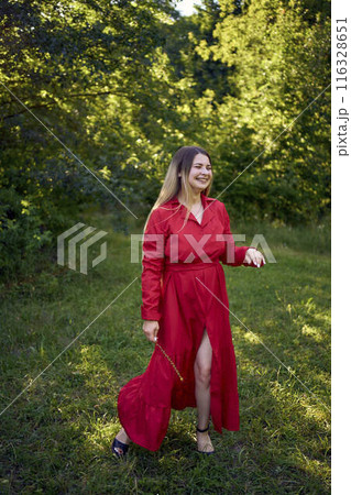 portrait of a beautiful 30-year-old woman with long blond hair in a red dress in a park portrait of a beautiful 30-year-old woman with long blond hair in a red dress in a park 116328651
