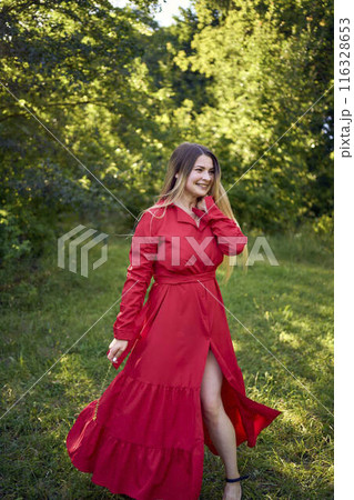 portrait of a beautiful 30-year-old woman with long blond hair in a red dress in a park portrait of a beautiful 30-year-old woman with long blond hair in a red dress in a park 116328653
