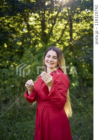 portrait of a beautiful 30-year-old woman with long blond hair in a red dress in a park portrait of a beautiful 30-year-old woman with long blond hair in a red dress in a park 116328742