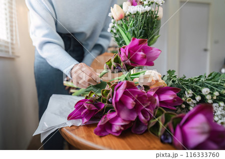 Florist Arranging Colorful Flowers on Wooden Table in Bright Room with Natural Light Florist Arranging Colorful Flowers on Wooden Table in Bright Room with Natural Light 116333760
