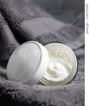 White opened cosmetic jar with white blank lid on grey folded towels in bath, packaging mockup White opened cosmetic jar with white blank lid on grey folded towels in bath, packaging mockup 116335085
