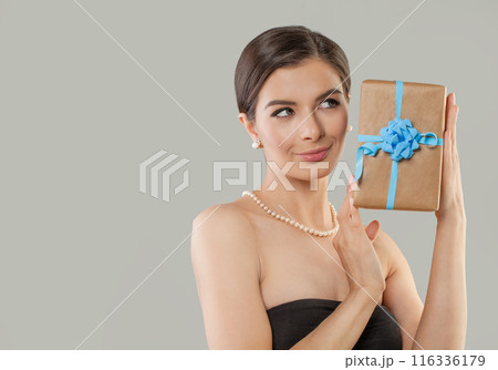 Young woman holding gift present on grey studio background. Celebration and Holidays concept Young woman holding gift present on grey studio background. Celebration and Holidays concept 116336179