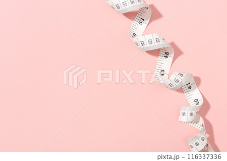 Measuring tape on pink background with copy space. Weight or length concept 116337336