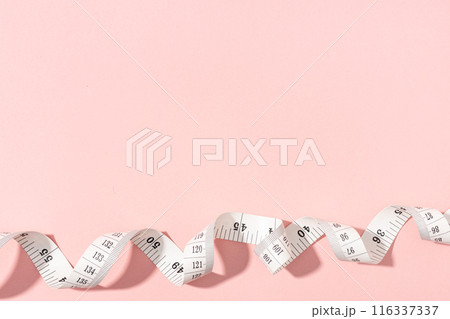 Measuring tape on pink background with copy space. Weight or length concept 116337337