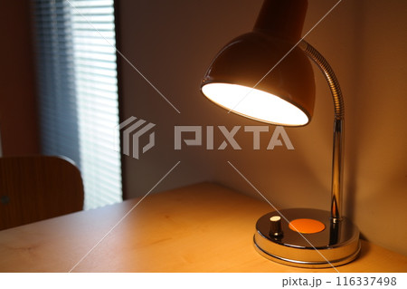 Lamp on a table in a room with window blinds 116337498
