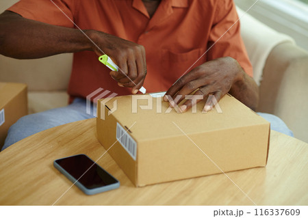Man Unpacking Cardboard Box At Table 116337609
