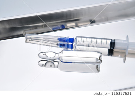 Syringes with needles and an ampoule in a stainless steel medical tray. 116337621
