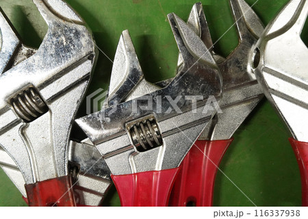 Adjustable wrench on the green background, closeup of photo Adjustable wrench on the green background, closeup of photo 116337938