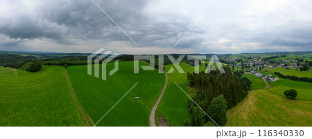Experience the scenic view of green hills and a charming countryside village in this panorama 116340330