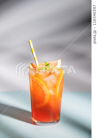Fresh grapefruit juice with ice, mint and grapefruit slice in a glass on a blue background  116340397