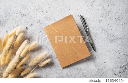 Home office workspace layout with a craft notebook, pen and dried bouquet on gray background Home office workspace layout with a craft notebook, pen and dried bouquet on gray background 116340404