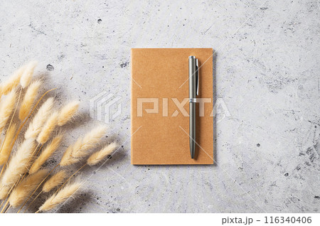 Home office workspace layout with a craft notebook, pen and dried bouquet on gray background Home office workspace layout with a craft notebook, pen and dried bouquet on gray background 116340406