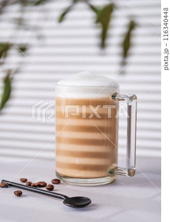 Cappuccino or latte with milk foam in a cup with coffee beans on light background  116340448