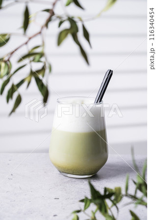 Japanese matcha latte, green tea with soy milk and spoon in glass on  light background  116340454