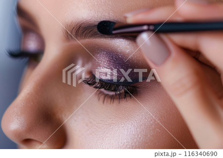 Closeup of womans eye as she applies eyeshadow with a makeup brush. Detailed makeup artistry 116340690