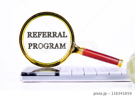 REFERRAL PROGRAM word. text written through a magnifying glass standing on a calculator on a white background REFERRAL PROGRAM word. text written through a magnifying glass standing on a calculator on a white background 116341659
