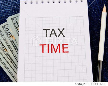 Business and tax concept. TAX TIME in a notebook in a composition with American hundred dollar bills and a pencil Business and tax concept. TAX TIME in a notebook in a composition with American hundred dollar bills and a pencil 116341669