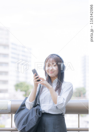 街中で音楽を聴きながらスマホを使う女子高生 街中で音楽を聴きながらスマホを使う女子高生 116342066