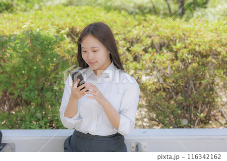 街中で座ってスマホを使う女子高生 116342162
