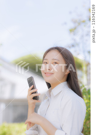 街中で座ってスマホを使う女子高生 116342169