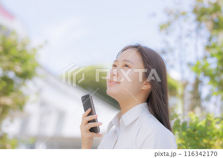 街中で座ってスマホを使う女子高生 116342170