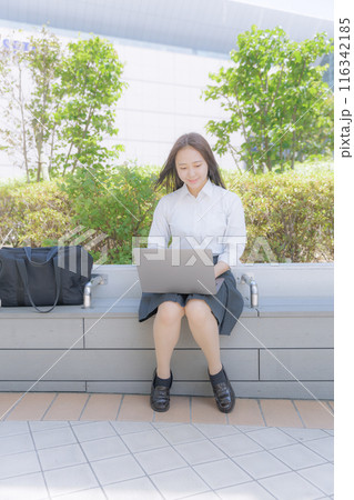 街中で座ってパソコン使う女子高生 116342185