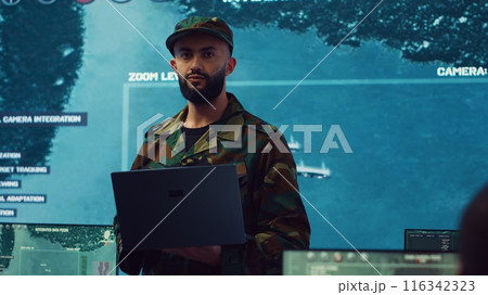 Army general managing air traffic control for military aircraft within the operational area, uses radar surveillance. Follows vessels on navy reconnaissance satellite system, big screen. Camera A. 116342323
