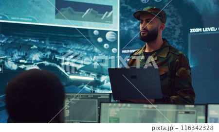 Special operations soldier allocating resources to different units based on mission needs, examines strategic data on a big screen in military control center. Marine corps troops. Camera A. Special operations soldier allocating resources to different units based on mission needs, examines strategic data on a big screen in military control center. Marine corps troops. Camera A. 116342328
