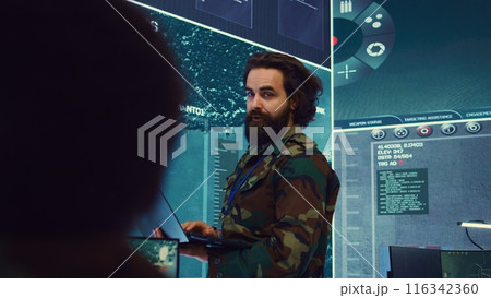 Army major monitoring data on a big screen in military command center, gathering information to execute a field mission. Captain leading his troops on a secret service defense operation. Camera B. Army major monitoring data on a big screen in military command center, gathering information to execute a field mission. Captain leading his troops on a secret service defense operation. Camera B. 116342360