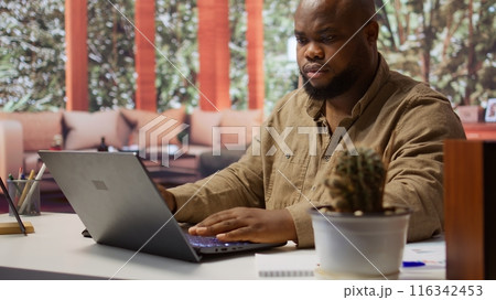 Self employed analyst working on financial audits and budget planning on his laptop, managing online marketing and development strategies for his personal trading business at home. Camera B. 116342453
