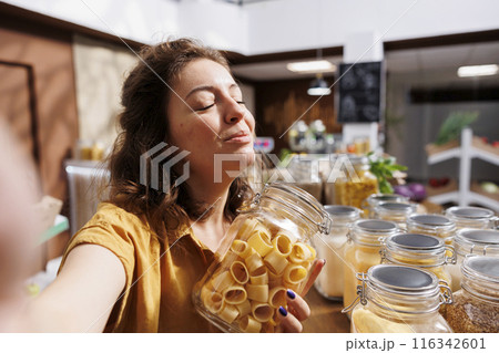 Influencer making internet video for social media, presenting eco friendly zero waste store. Sustainable lifestyle vlogger filming herself inside bulk products local grocery shop 116342601