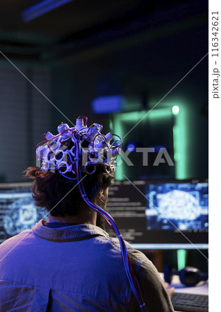 Engineer with EEG headset on programming brain transfer into computer virtual world, merging with artificial intelligence. Transhumanist using neuroscience to gain digital soul 116342621