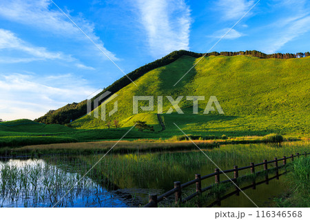 2024年夏曽爾高原の夕景　夕日を受けて美しい山肌を見せる倶留尊山と豊かな水を湛えたお亀池　横構図② 116346568