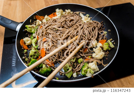 Chef at the kitchen preparing japanese buckwheat pasta with lentils 116347243