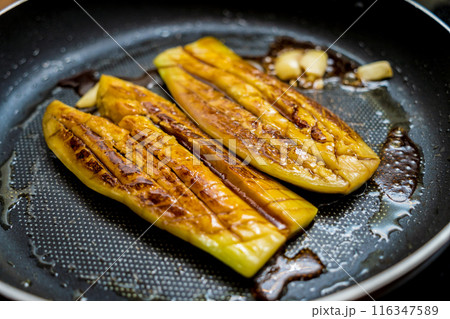 Delicious grilled eggplants with garlic on the fried pan Delicious grilled eggplants with garlic on the fried pan 116347589