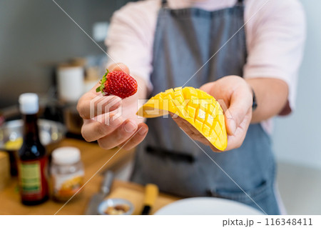 Chef at the kitchen preparing bowl of oats with strawberries and mango Chef at the kitchen preparing bowl of oats with strawberries and mango 116348411