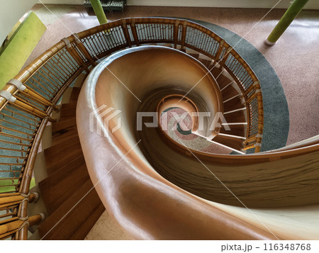 There is a spiral staircase in a building with a wooden railing There is a spiral staircase in a building with a wooden railing 116348768