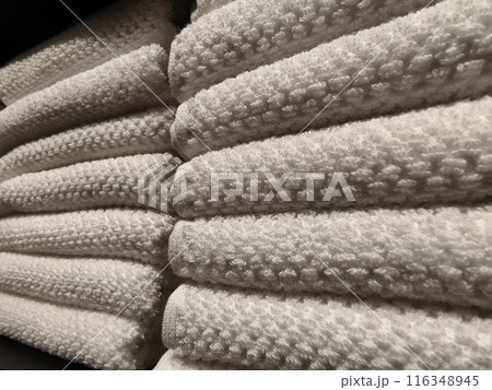 A stack of white towels neatly arranged on a black shelf 116348945