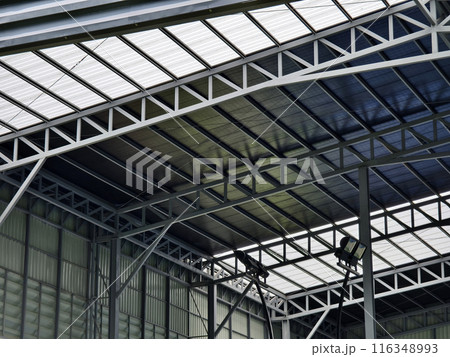 A large building with metal roof against a cloudy sky 116348993