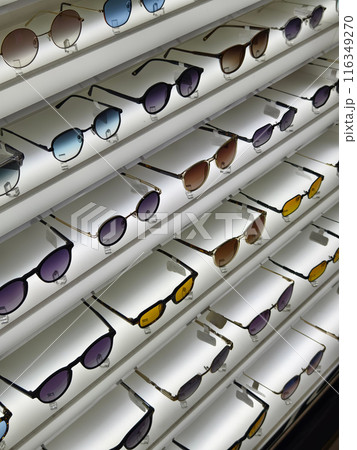 There are multiple pairs of sunglasses arranged neatly on a shelf 116349270