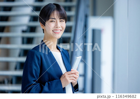 オフィスでスマホを操作するスーツ姿の若い女性 116349682