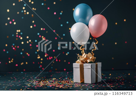 A box of white balloons with gold ribbons sits on a table covered in confetti 116349713